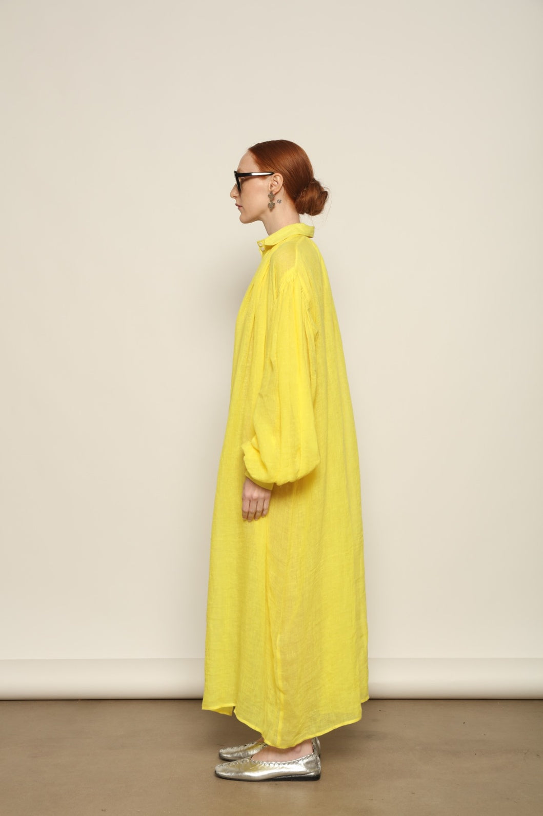 Model is wearing the Les Vacances d’Irina Carmen Linen Dress in Yellow, handcrafted from linen with dramatic wide sleeves, from the House of Nomad Stories selection.
