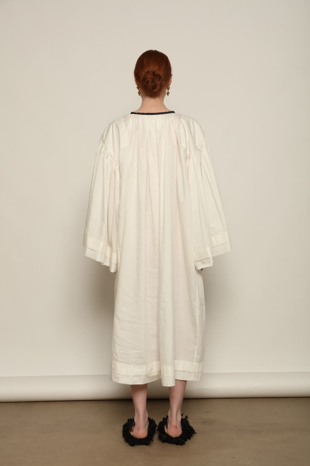 Model is wearing the Les Vacances d’Irina Favignana Dress in White, handcrafted from cotton and silk with multilayered sleeves and hand-sewn pleating, from the House of Nomad Stories selection.