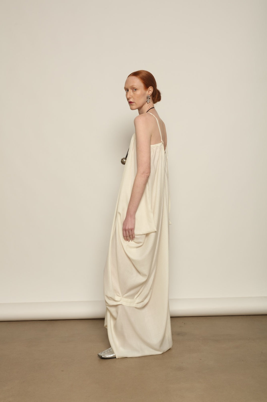 Model is wearing the Les Vacances d’Irina Grande Bellezza Ivory Dress, a sculptural draped full-length dress handcrafted in Bucharest, from the House of Nomad Stories selection.