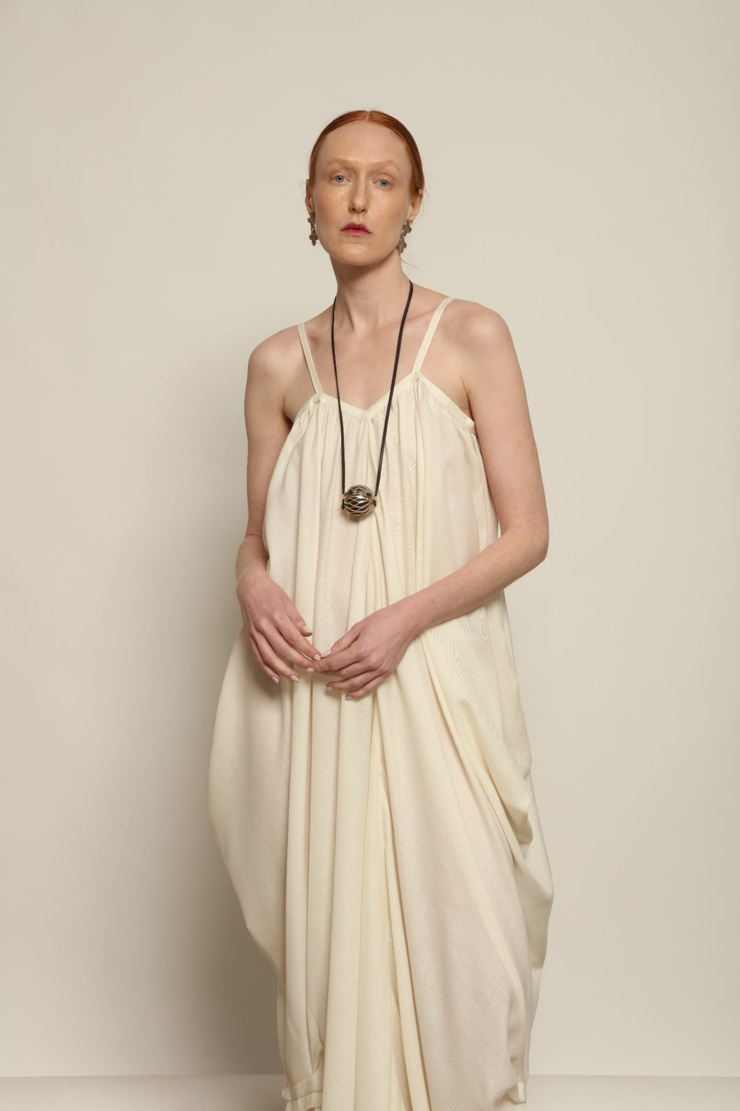 Model is wearing the Les Vacances d’Irina Grande Bellezza Ivory Dress, a sculptural draped full-length dress handcrafted in Bucharest, from the House of Nomad Stories selection.