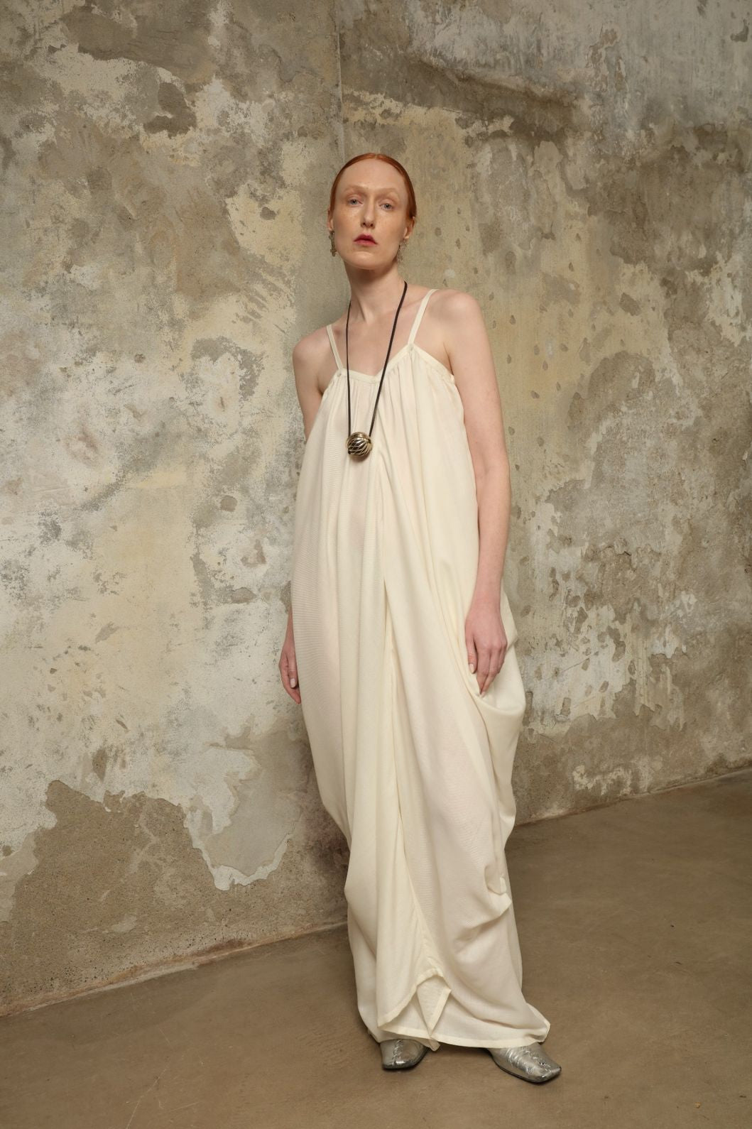 Model is wearing the Les Vacances d’Irina Grande Bellezza Ivory Dress, a sculptural draped full-length dress handcrafted in Bucharest, from the House of Nomad Stories selection.