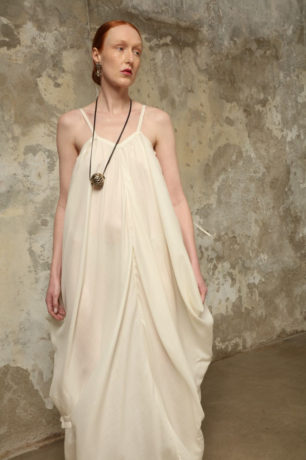 Model is wearing the Les Vacances d’Irina Grande Bellezza Ivory Dress, a sculptural draped full-length dress handcrafted in Bucharest, from the House of Nomad Stories selection.