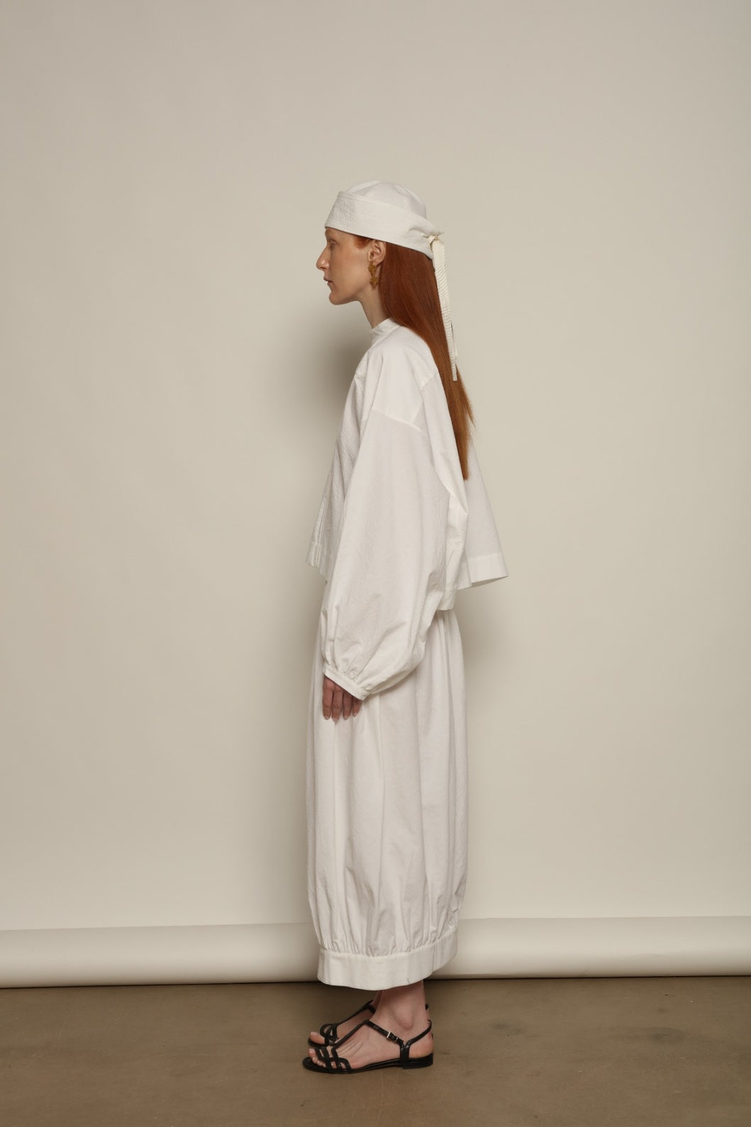 Model is wearing the Les Vacances d’Irina Jade white cotton skirt with high waist and double-breasted button front, from the House of Nomad Stories selection.