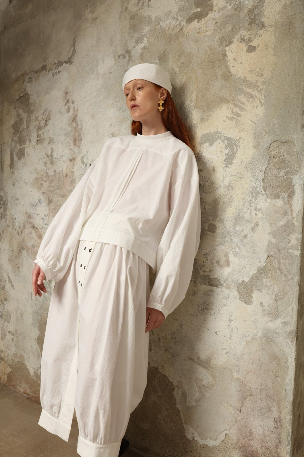 Model is wearing the Les Vacances d’Irina Jade white cotton skirt with high waist and double-breasted button front, from the House of Nomad Stories selection.