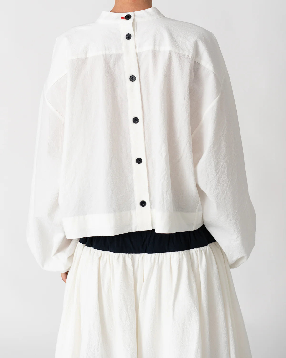 Model is wearing the Les Vacances d’Irina white cotton blouse in 100% cotton with voluminous sleeves and pleated front, from the House of Nomad Stories selection.
