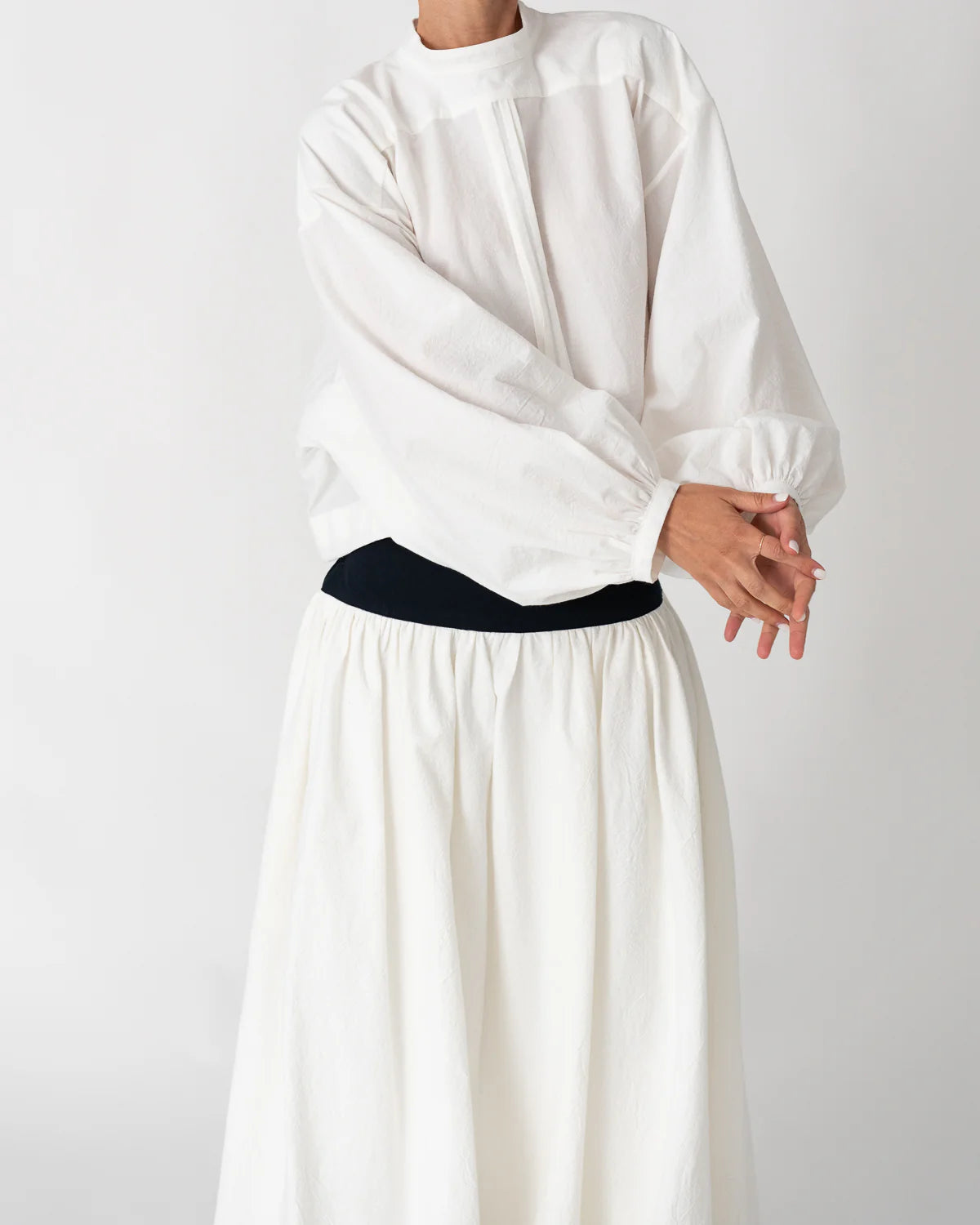 Model is wearing the Les Vacances d’Irina white cotton blouse in 100% cotton with voluminous sleeves and pleated front, from the House of Nomad Stories selection.