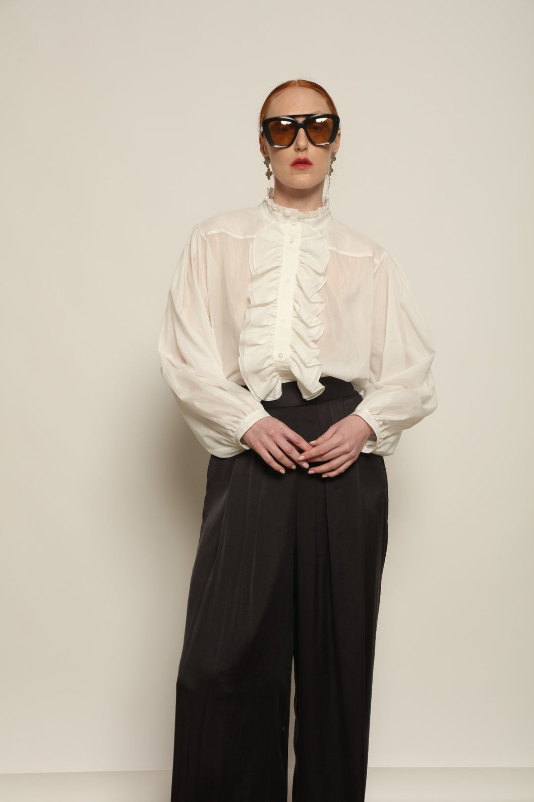 Model is wearing the Les Vacances d’Irina Victorian White Blouse with ruffled collar, front frills and voluminous sleeves, handcrafted in Bucharest, from the House of Nomad Stories selection.