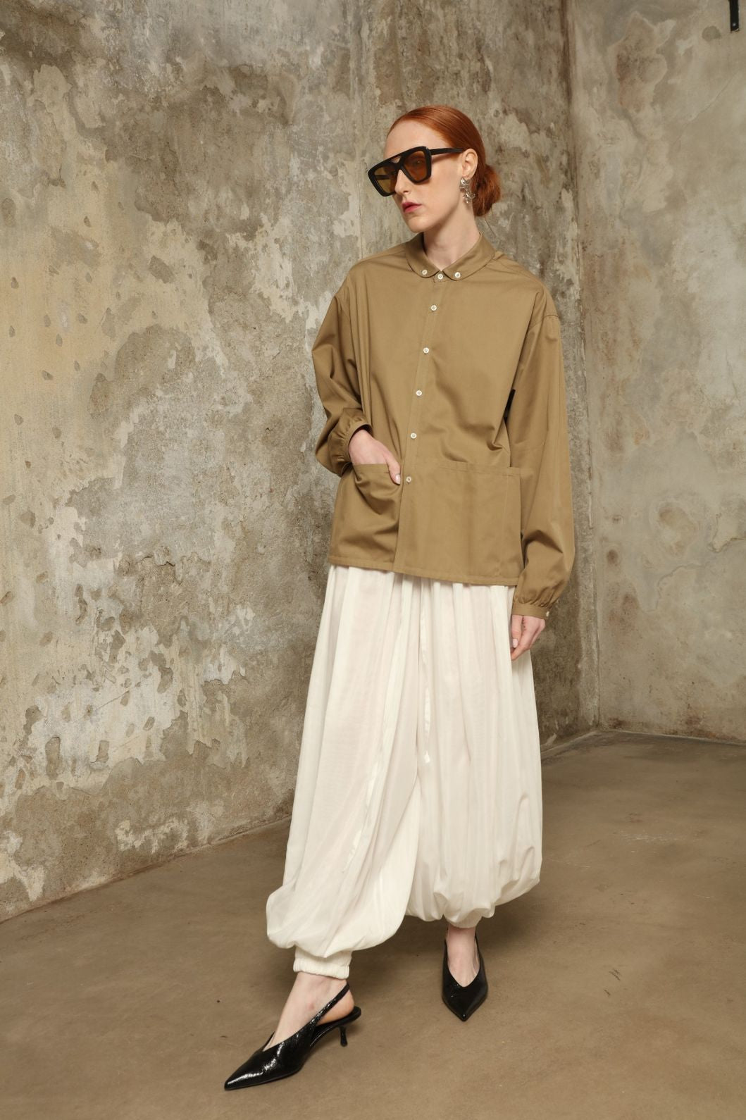 Model is wearing the Les Vacances d’Irina Vulcano White Pants, handcrafted from 100% cotton with a balloon silhouette and gathered ankles, from the House of Nomad Stories selection.