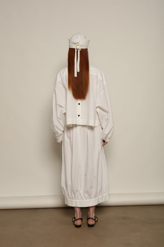 Model is wearing the Les Vacances d’Irina white cotton blouse in 100% cotton with voluminous sleeves and pleated front, from the House of Nomad Stories selection.