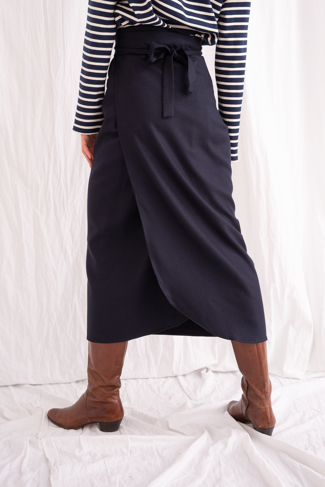 Model is wearing the Wrapped Wool Skirt by Les Vacances d’Irina, a mid-length dark-navy handmade wool skirt with fluid wrap design, available at House of Woven Stories.