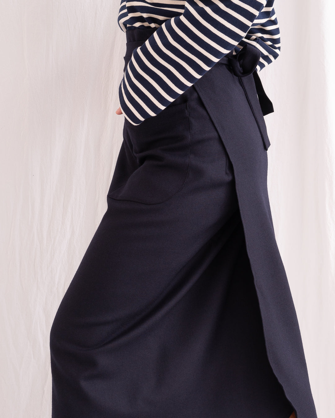 Model is wearing the Wrapped Wool Skirt by Les Vacances d’Irina, a mid-length dark-navy handmade wool skirt with fluid wrap design, available at House of Woven Stories.