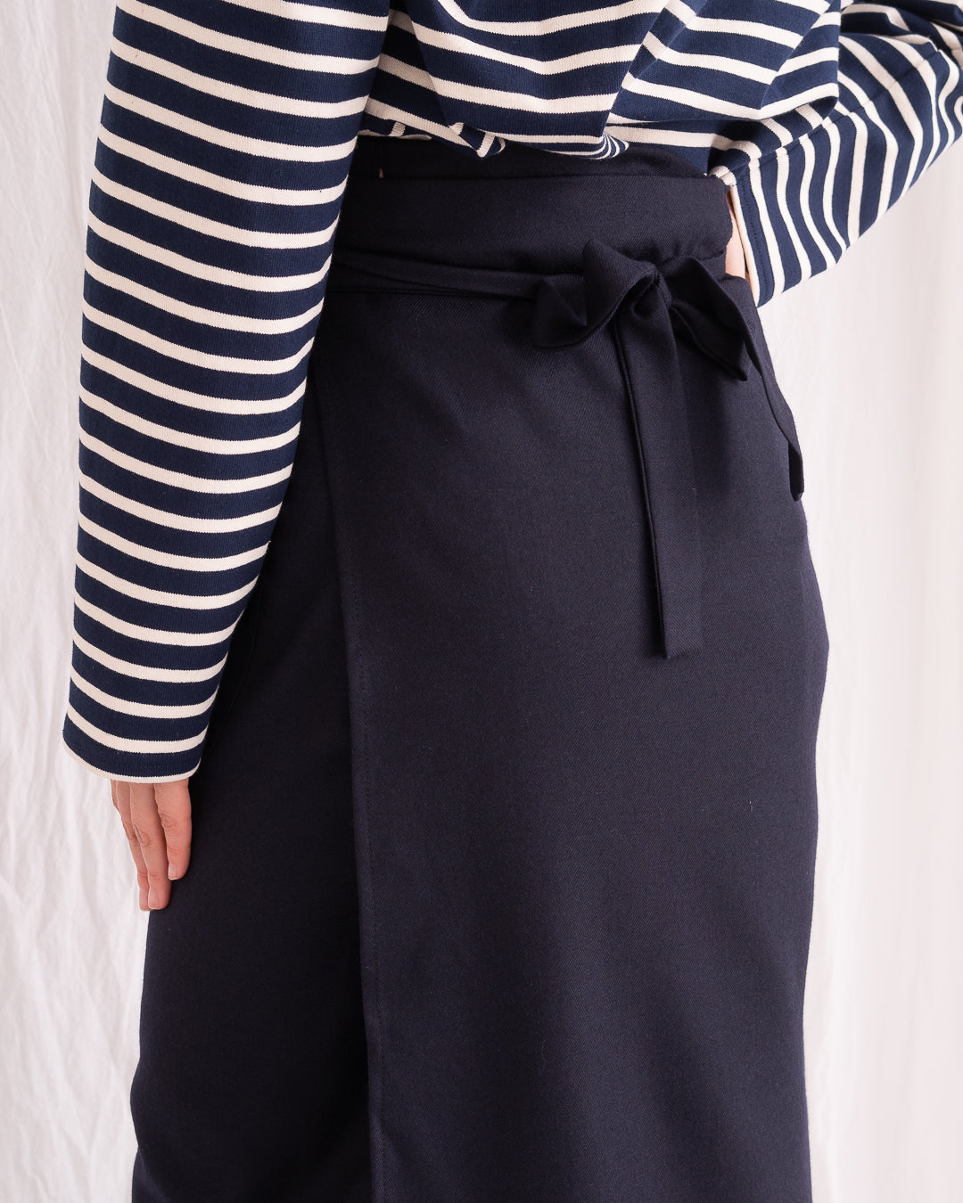 Model is wearing the Wrapped Wool Skirt by Les Vacances d’Irina, a mid-length dark-navy handmade wool skirt with fluid wrap design, available at House of Woven Stories.