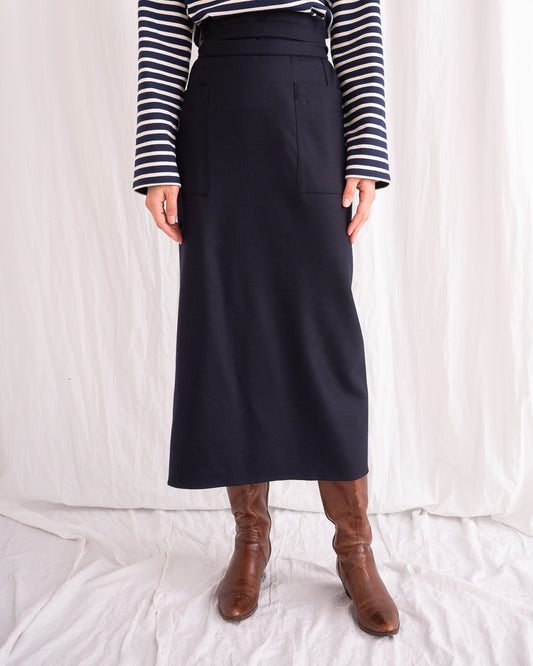 Model is wearing the Wrapped Wool Skirt by Les Vacances d’Irina, a mid-length dark-navy handmade wool skirt with fluid wrap design, available at House of Woven Stories.