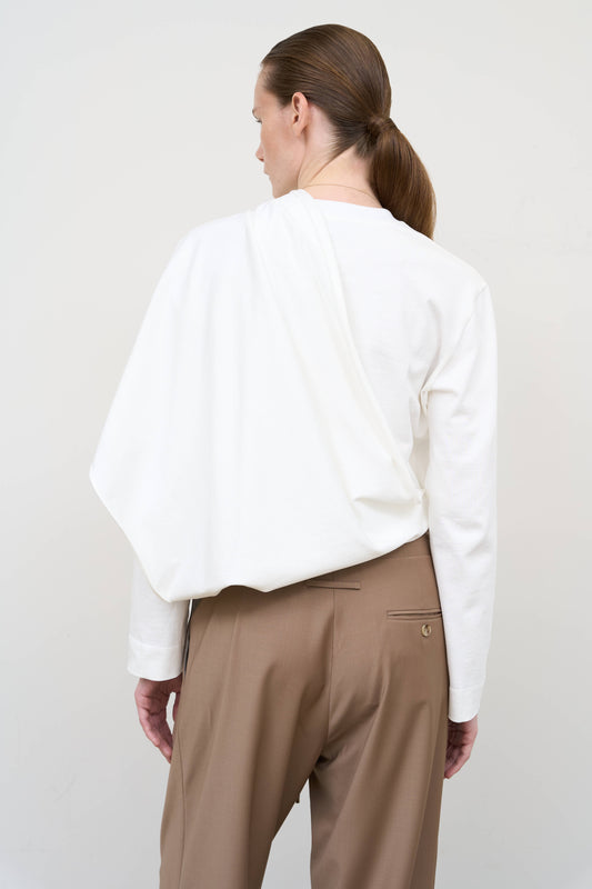 Model is wearing a white asymmetric cotton longsleeve by Litkovska with elongated silhouette and subtle architectural asymmetry, designer women’s top available at House of Woven Stories