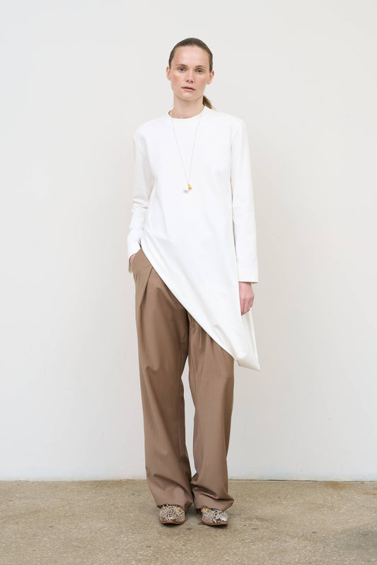 Model is wearing a white asymmetric cotton longsleeve by Litkovska with elongated silhouette and subtle architectural asymmetry, designer women’s top available at House of Woven Stories