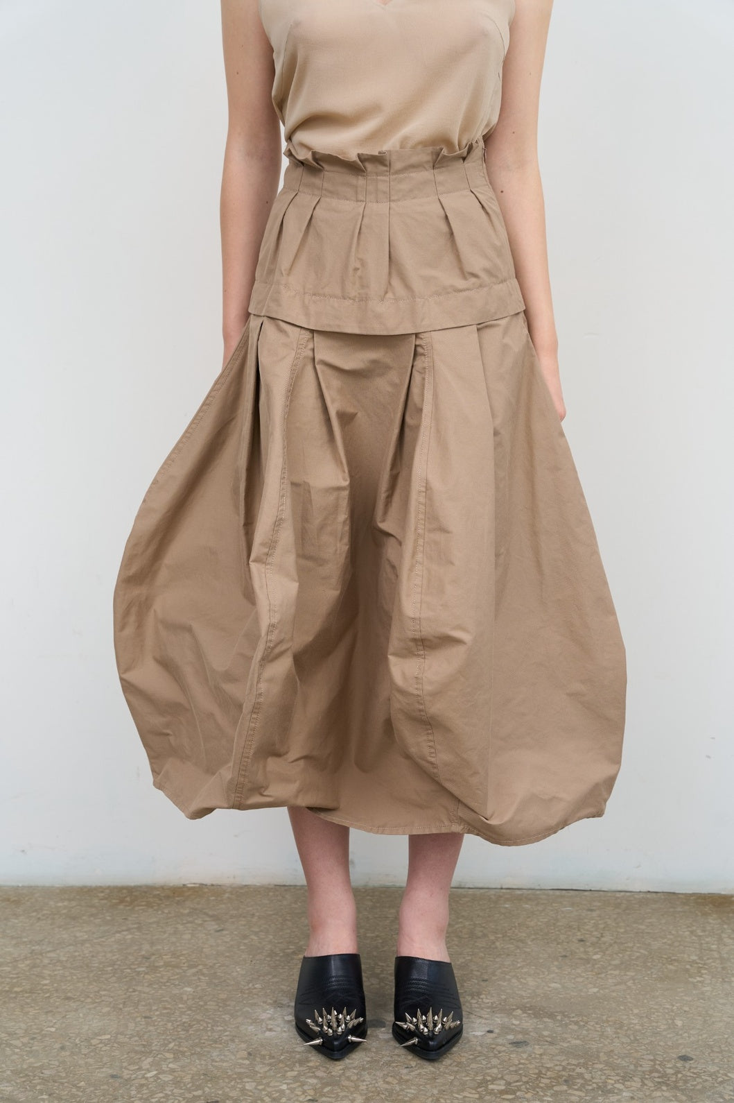 Model is wearing Litkovska beige ruffled midi skirt with pleated waist and voluminous balloon hem. A sculptural, modern, and artisanal piece that belongs to the curated selection of House of Nomad Stories.