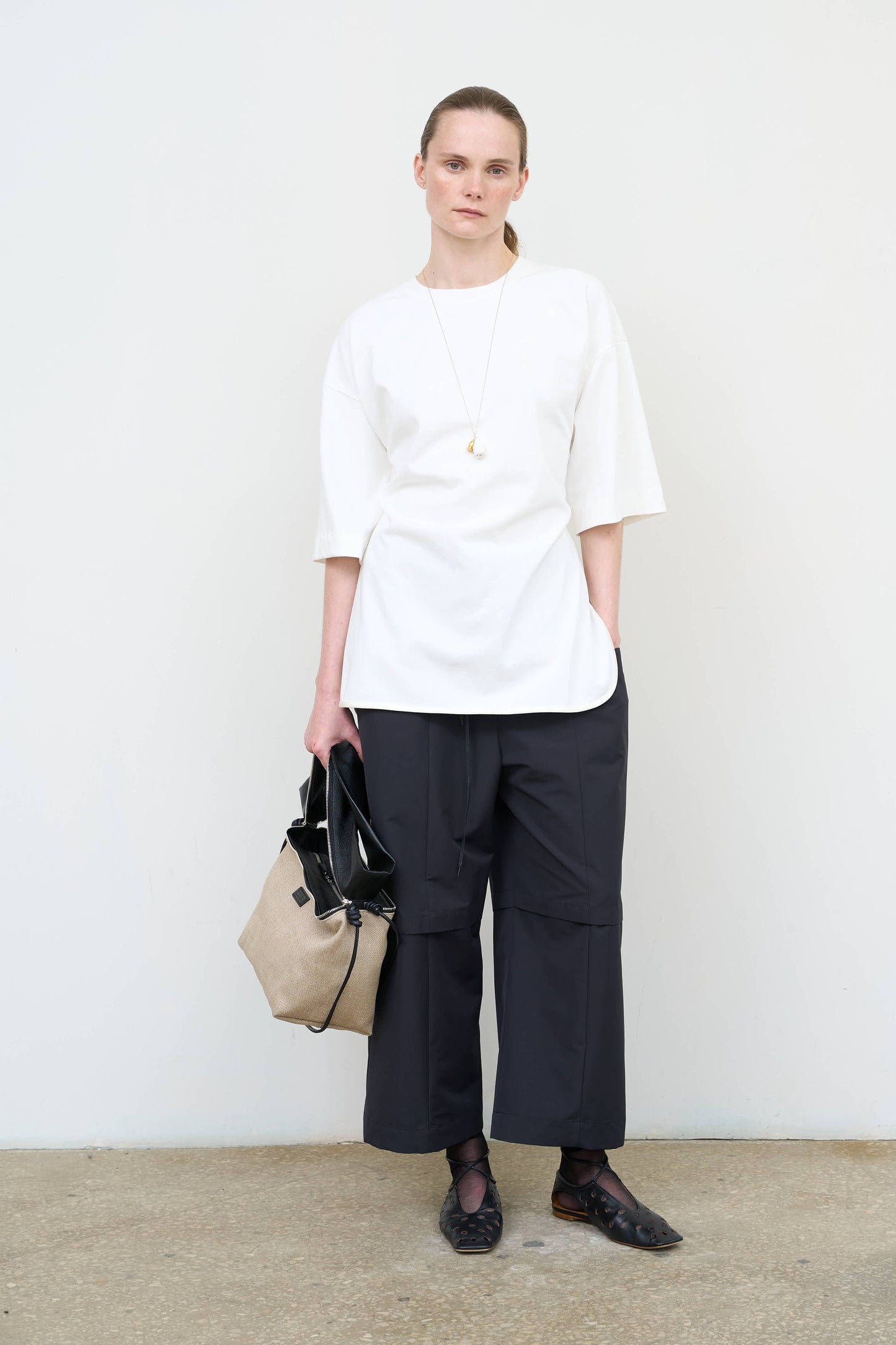 Model is wearing a white Corset T-Shirt by Litkovska with integrated corset-inspired waist panel and relaxed silhouette, designer women’s top available at House of Woven Stories