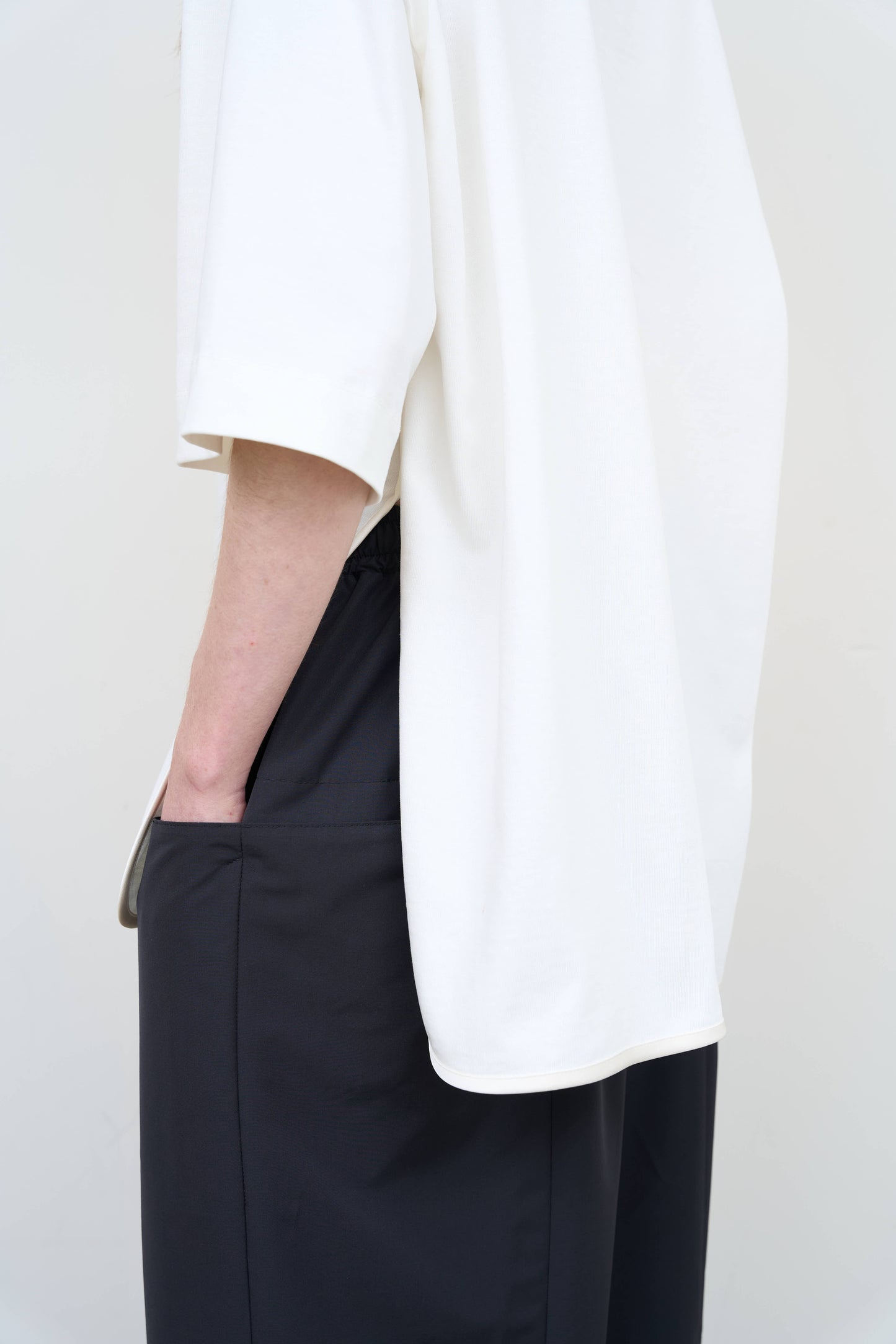 Model is wearing a white Corset T-Shirt by Litkovska with integrated corset-inspired waist panel and relaxed silhouette, designer women’s top available at House of Woven Stories