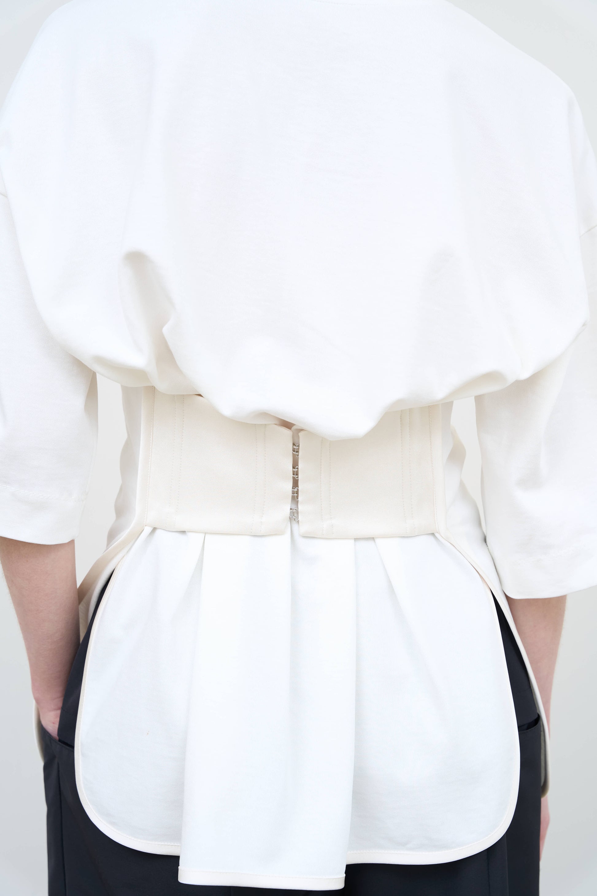 Model is wearing a white Corset T-Shirt by Litkovska with integrated corset-inspired waist panel and relaxed silhouette, designer women’s top available at House of Woven Stories