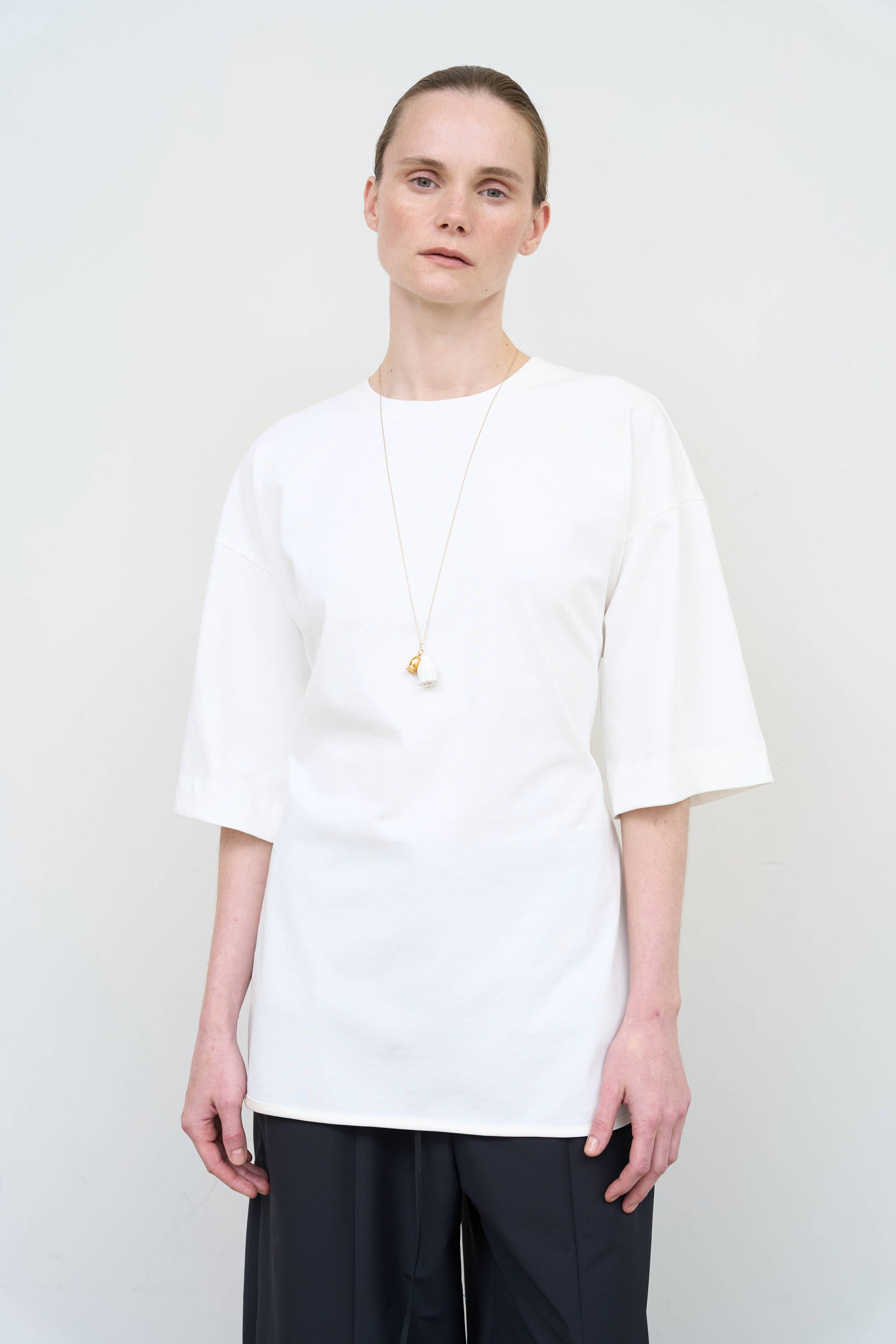 Model is wearing a white Corset T-Shirt by Litkovska with integrated corset-inspired waist panel and relaxed silhouette, designer women’s top available at House of Woven Stories