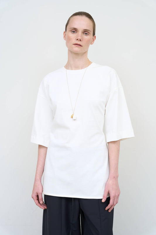 Model is wearing a white Corset T-Shirt by Litkovska with integrated corset-inspired waist panel and relaxed silhouette, designer women’s top available at House of Woven Stories