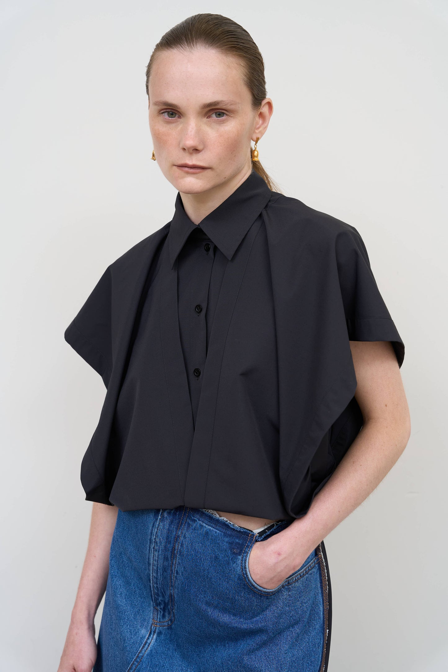 Model is wearing a deconstructed black wool-blend sleeveless shirt by Litkovska with architectural tailoring and elongated silhouette, designer women’s shirt available at House of Woven Stories