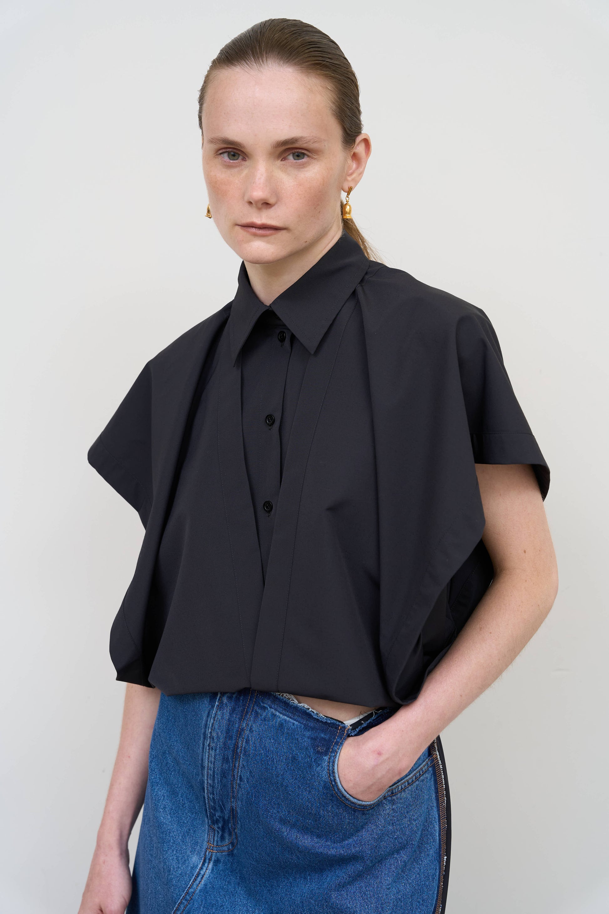 Model is wearing a deconstructed black wool-blend sleeveless shirt by Litkovska with architectural tailoring and elongated silhouette, designer women’s shirt available at House of Woven Stories