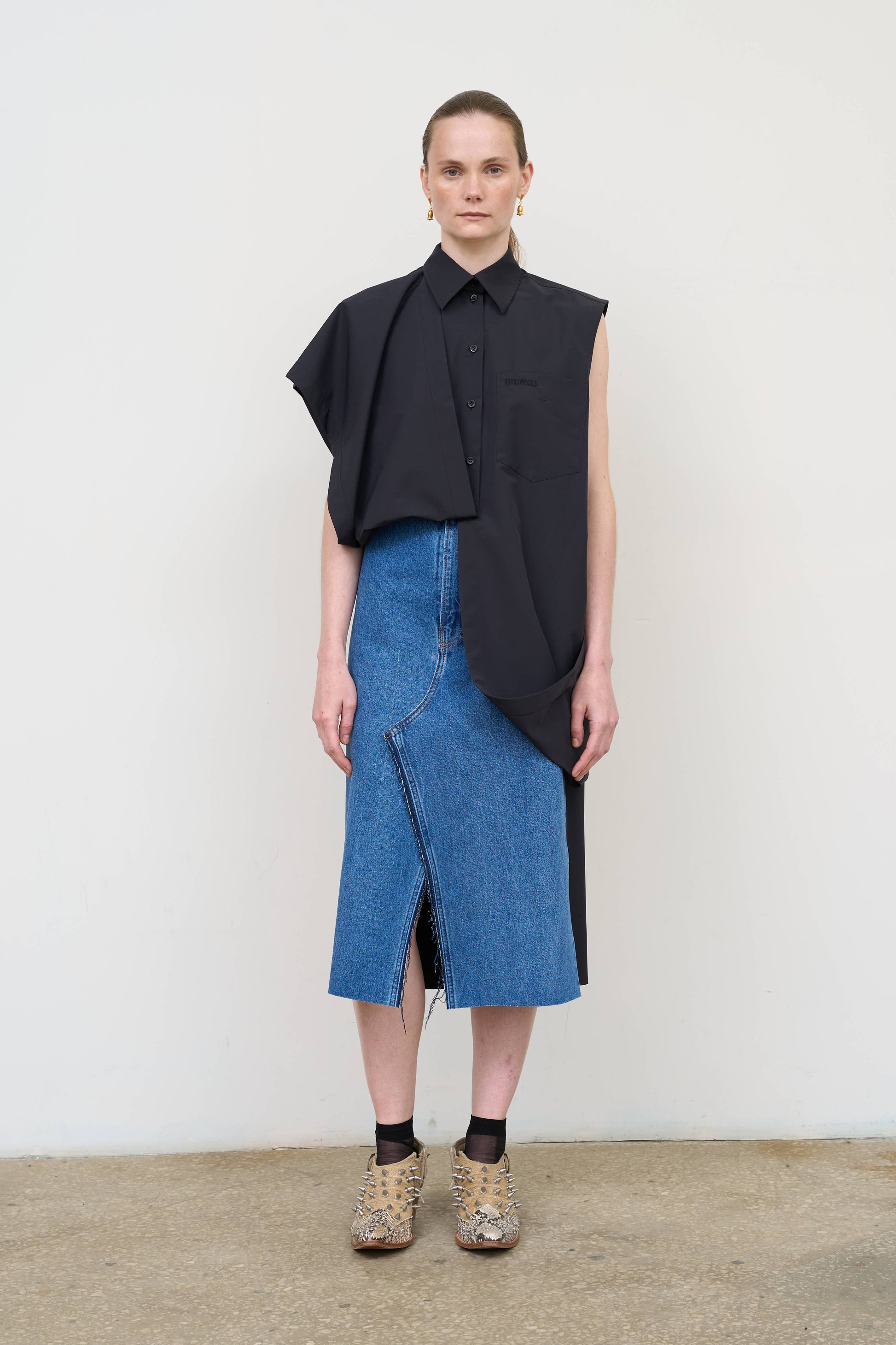 Model is wearing a deconstructed black wool-blend sleeveless shirt by Litkovska with architectural tailoring and elongated silhouette, designer women’s shirt available at House of Woven Stories