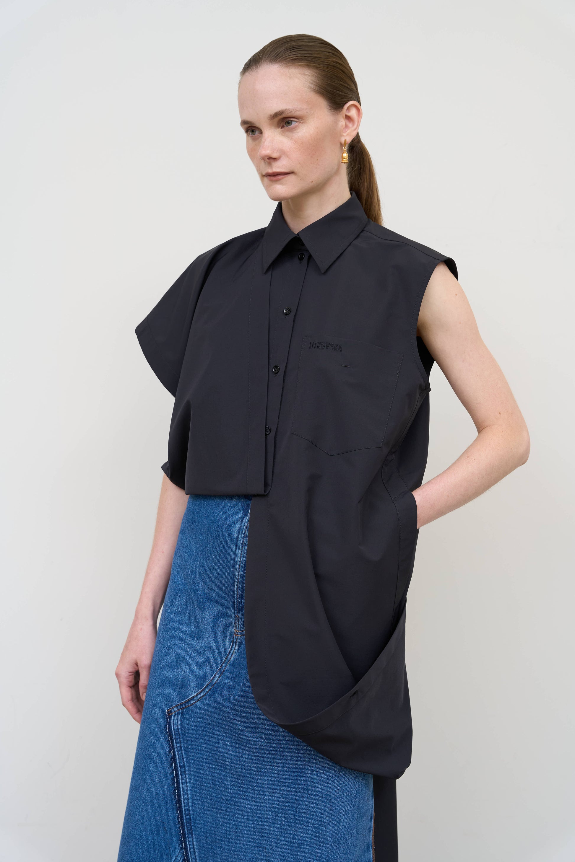 Model is wearing a deconstructed black wool-blend sleeveless shirt by Litkovska with architectural tailoring and elongated silhouette, designer women’s shirt available at House of Woven Stories