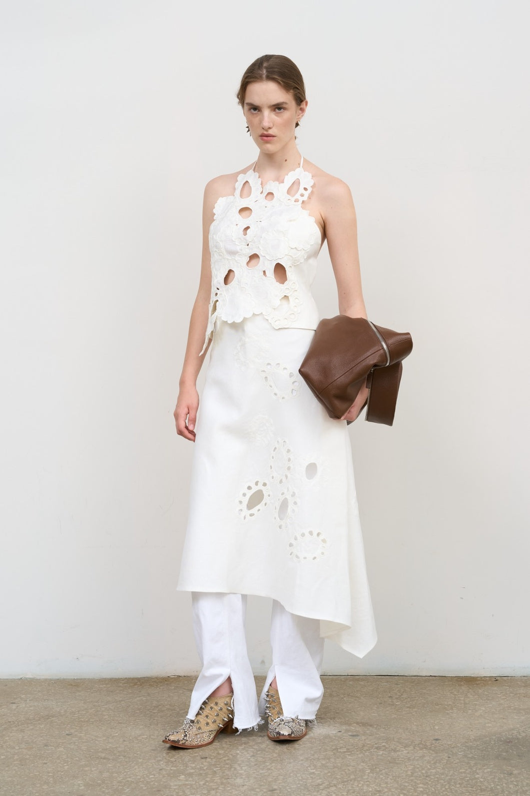 Model is wearing Litkovska white backless top with floral appliqué and sculptural cut-outs. A modern, artisanal, and timeless piece that belongs to the curated selection of House of Nomad Stories.