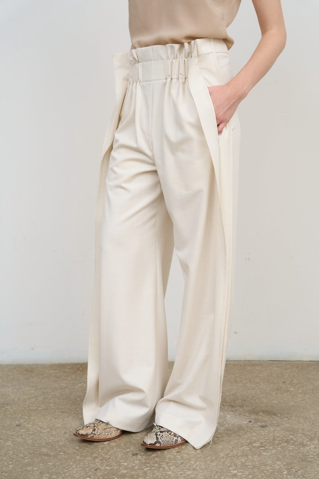 Model is wearing Litkovska high-rise pleated wide-leg ivory pants with tailored pleats and fluid silhouette. A modern, architectural, and timeless piece that belongs to the curated selection of House of Nomad Stories.