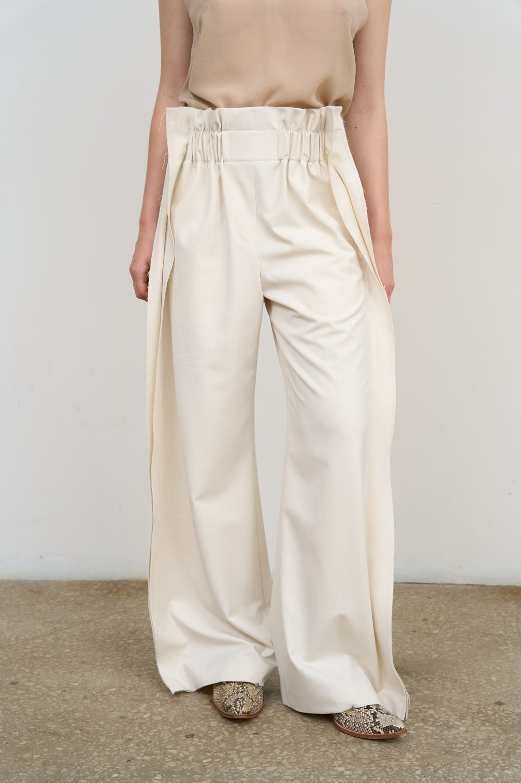 Model is wearing Litkovska high-rise pleated wide-leg ivory pants with tailored pleats and fluid silhouette. A modern, architectural, and timeless piece that belongs to the curated selection of House of Nomad Stories.