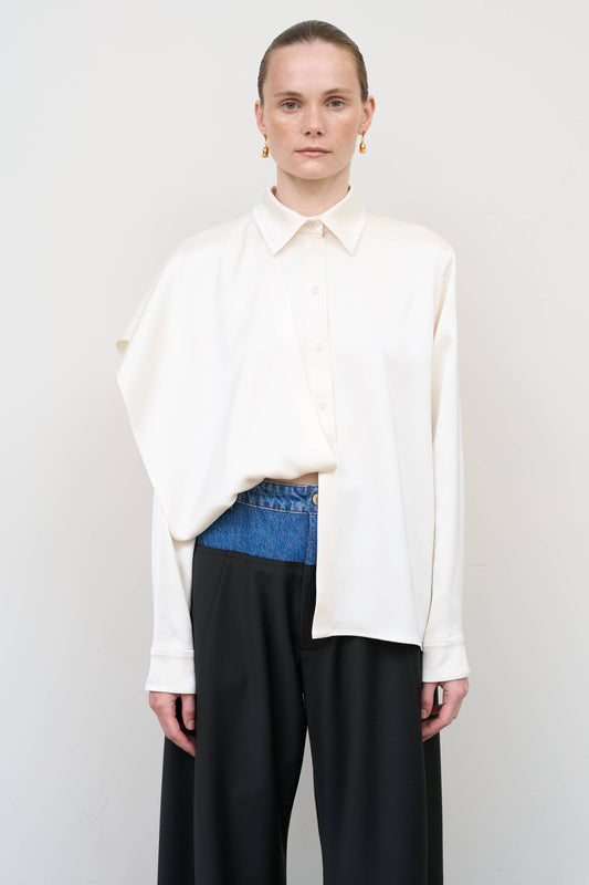 Model is wearing a layered ivory blouse by Litkovska with integrated scarf detail and asymmetrical design, designer women’s blouse available at House of Woven Stories
