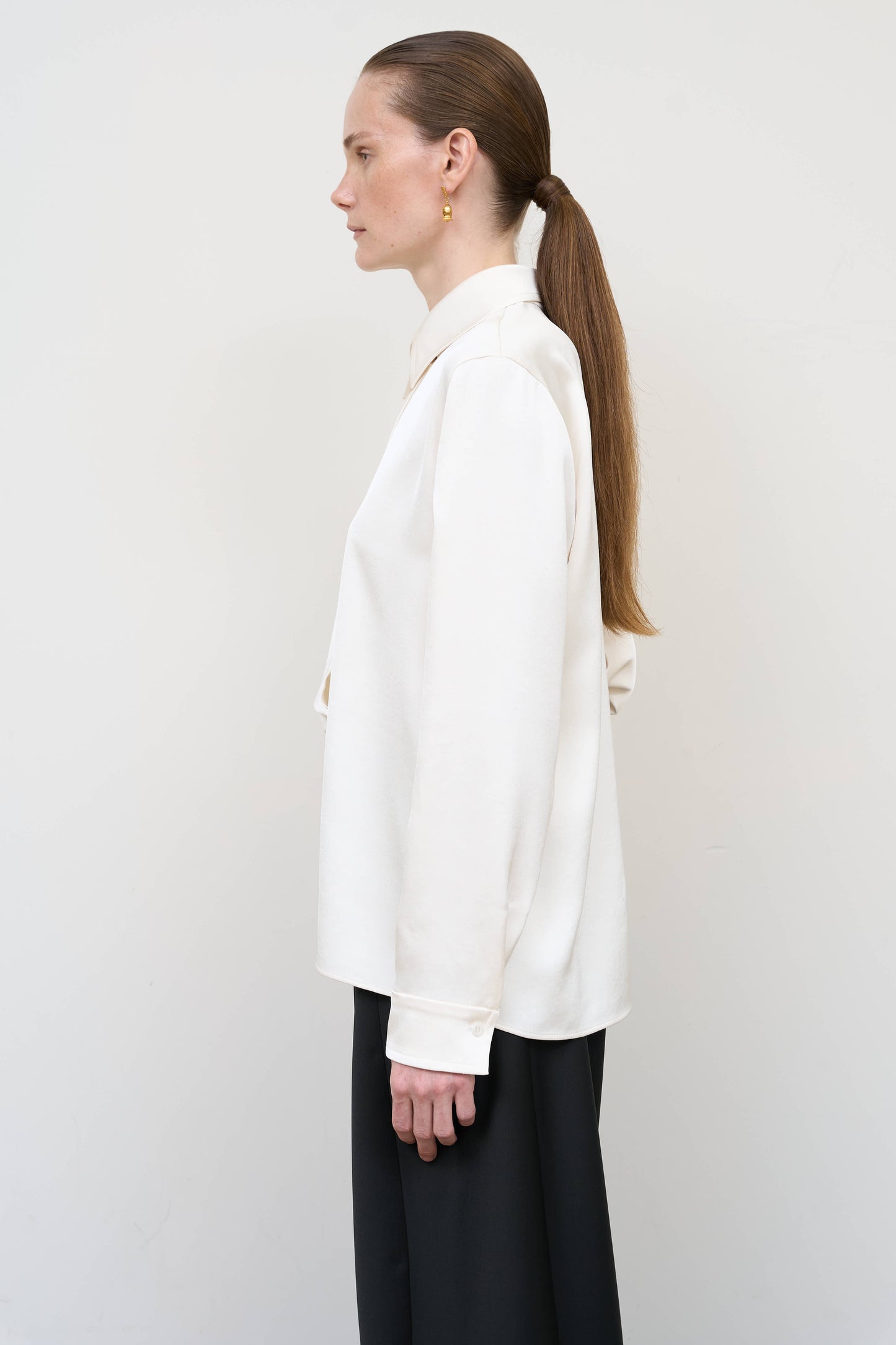 Model is wearing a layered ivory blouse by Litkovska with integrated scarf detail and asymmetrical design, designer women’s blouse available at House of Woven Stories