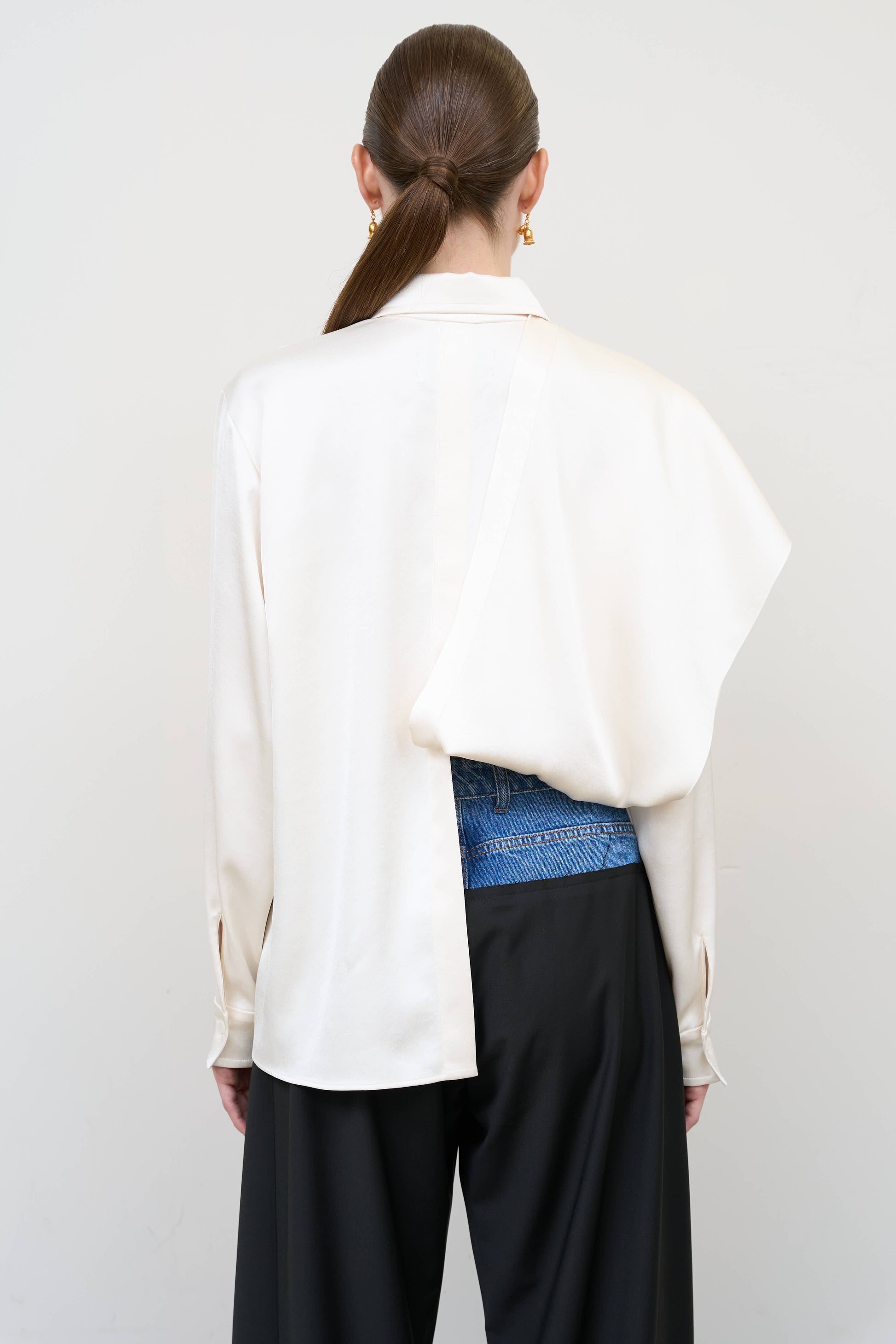 Model is wearing a layered ivory blouse by Litkovska with integrated scarf detail and asymmetrical design, designer women’s blouse available at House of Woven Stories