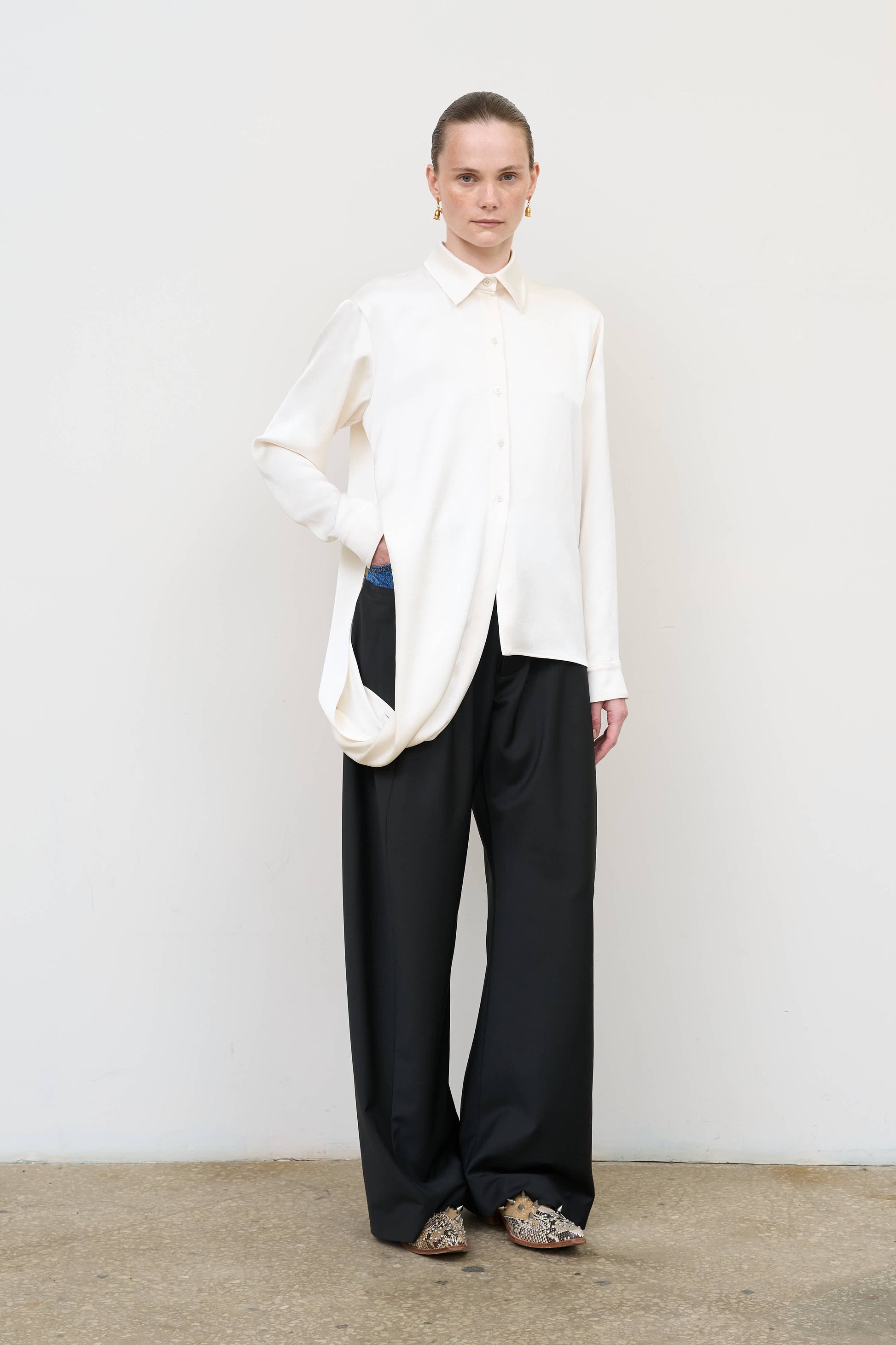 Model is wearing a layered ivory blouse by Litkovska with integrated scarf detail and asymmetrical design, designer women’s blouse available at House of Woven Stories