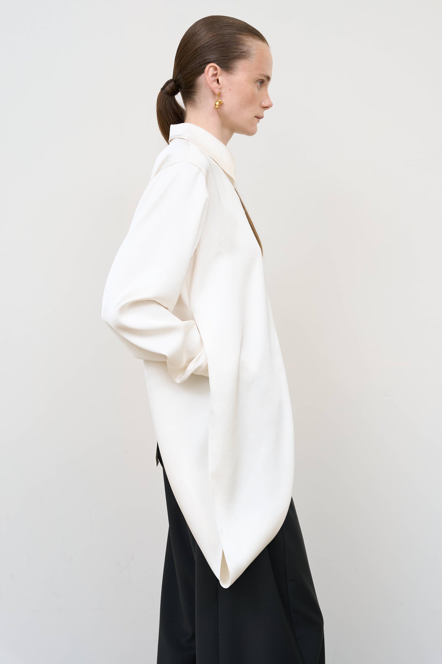 Model is wearing a layered ivory blouse by Litkovska with integrated scarf detail and asymmetrical design, designer women’s blouse available at House of Woven Stories