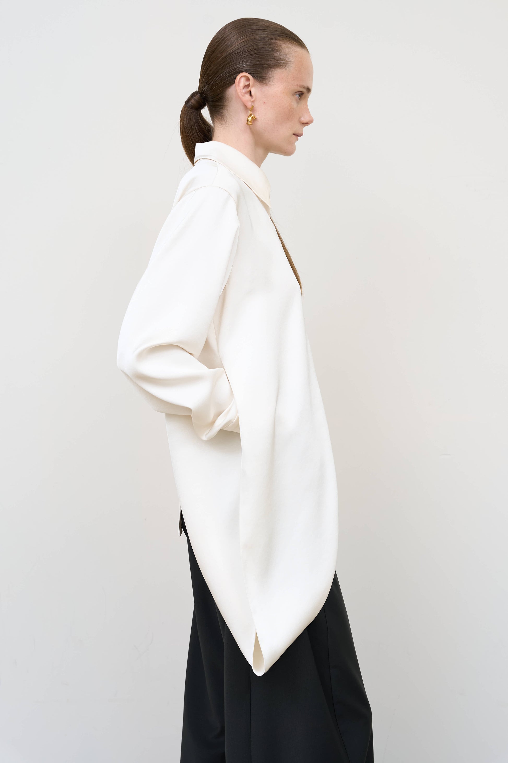 Model is wearing a layered ivory blouse by Litkovska with integrated scarf detail and asymmetrical design, designer women’s blouse available at House of Woven Stories
