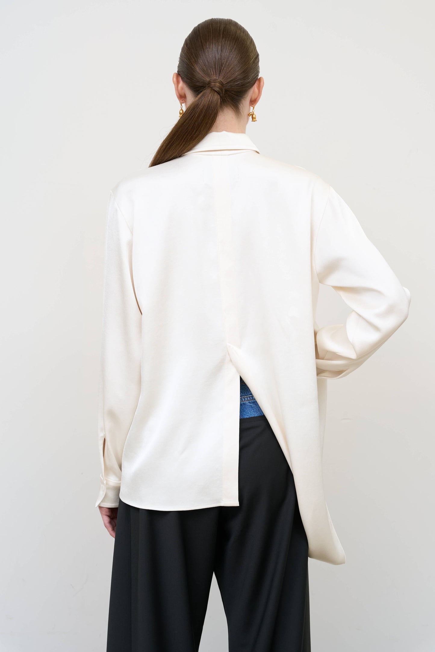 Model is wearing a layered ivory blouse by Litkovska with integrated scarf detail and asymmetrical design, designer women’s blouse available at House of Woven Stories
