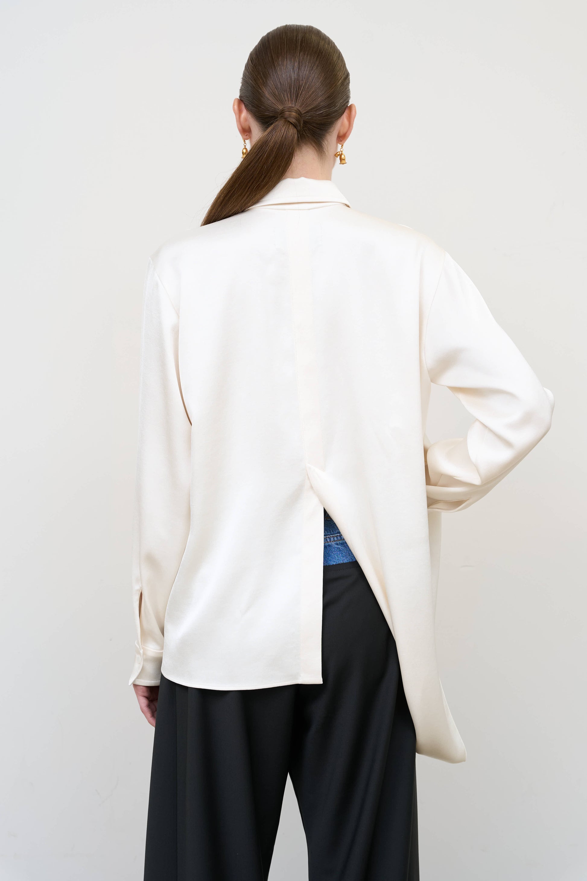 Model is wearing a layered ivory blouse by Litkovska with integrated scarf detail and asymmetrical design, designer women’s blouse available at House of Woven Stories