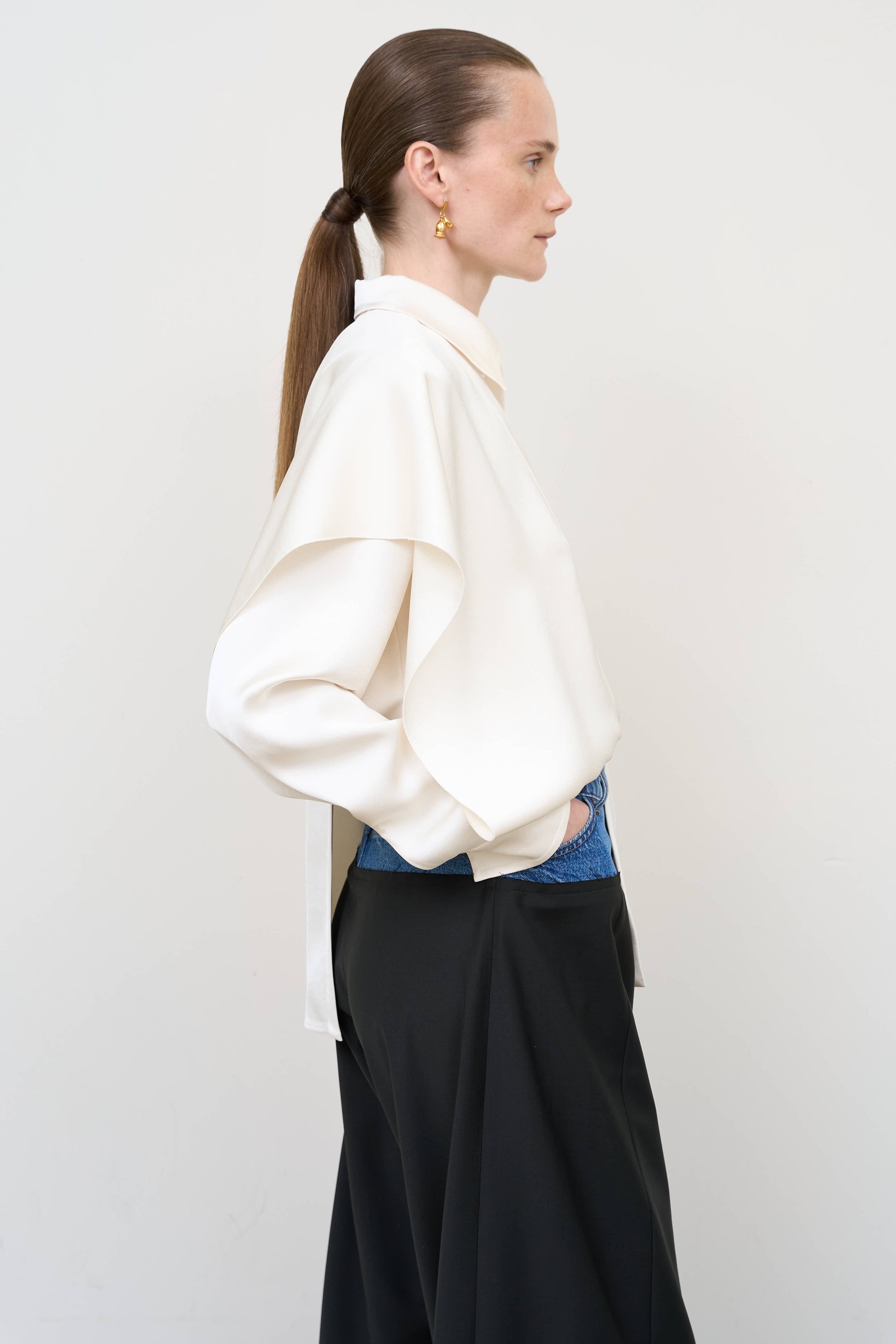 Model is wearing a layered ivory blouse by Litkovska with integrated scarf detail and asymmetrical design, designer women’s blouse available at House of Woven Stories