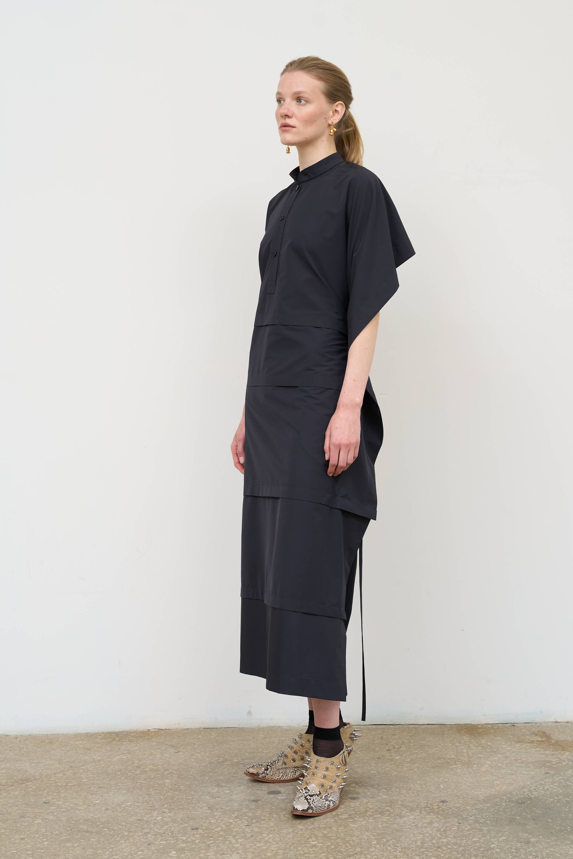Model is wearing a midi dress by Litkovska with capelet detail, layered wool-blend structure and cotton elements, designer women’s dress available at House of Woven Stories