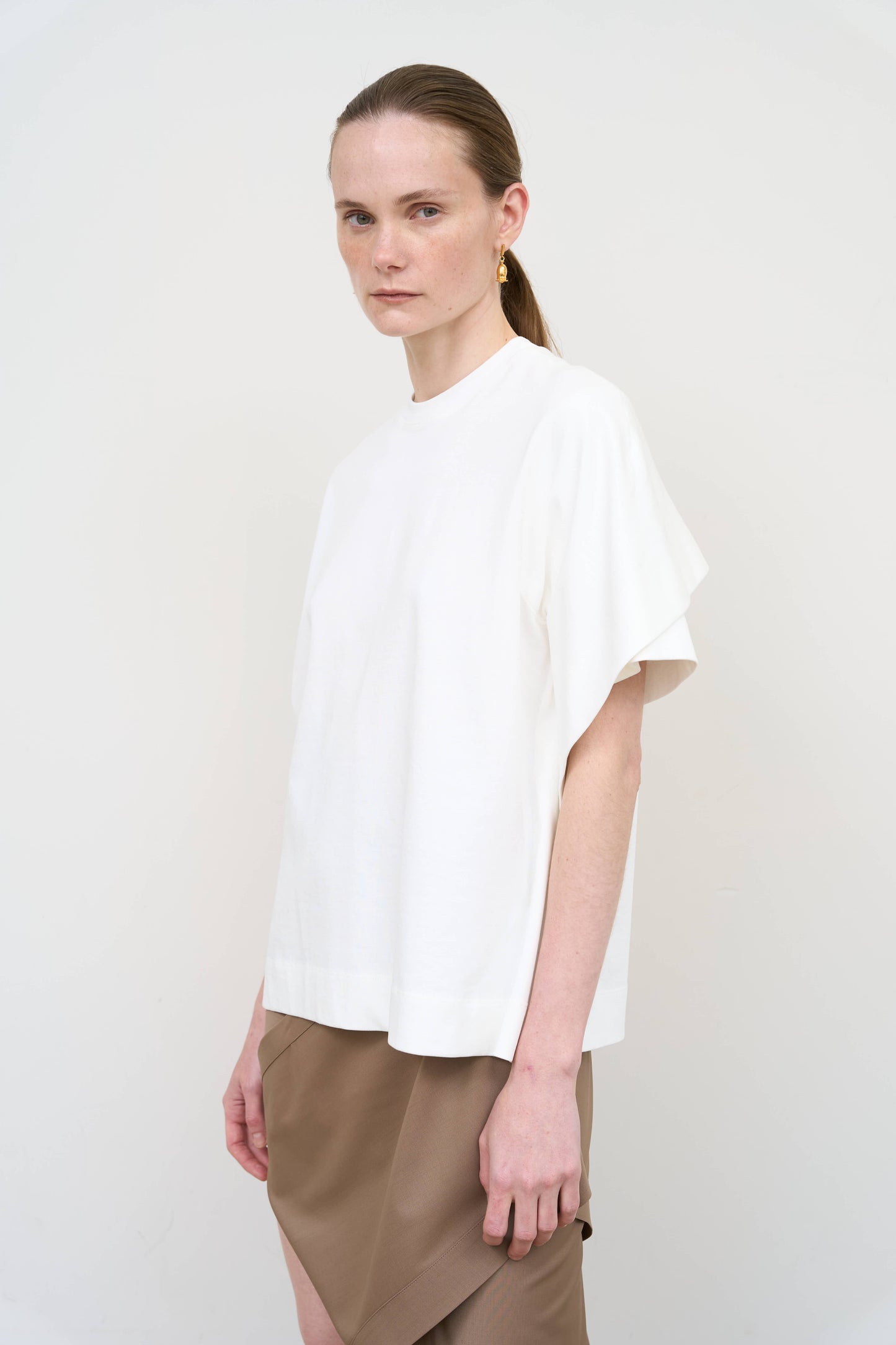 Model is wearing a white overlay cotton T-shirt by Litkovska with relaxed fit and layered architectural design, modern designer women’s T-shirt available at House of Woven Stories