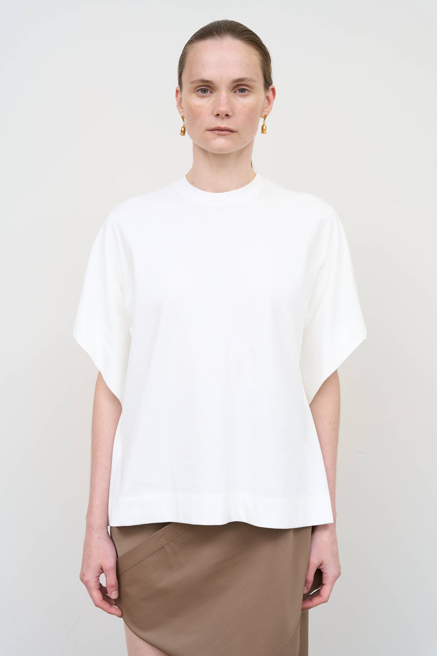 Model is wearing a white overlay cotton T-shirt by Litkovska with relaxed fit and layered architectural design, modern designer women’s T-shirt available at House of Woven Stories