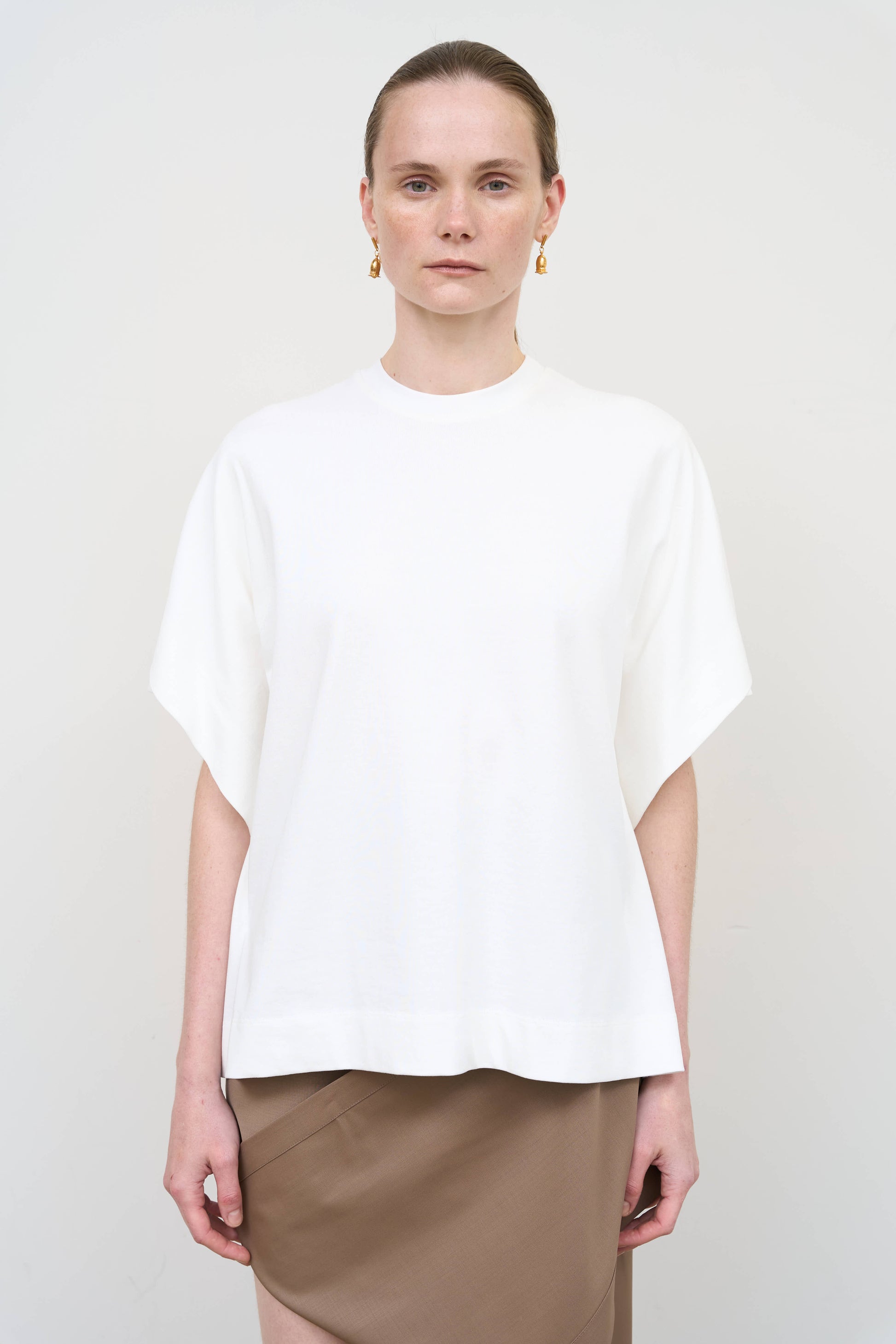 Model is wearing a white overlay cotton T-shirt by Litkovska with relaxed fit and layered architectural design, modern designer women’s T-shirt available at House of Woven Stories