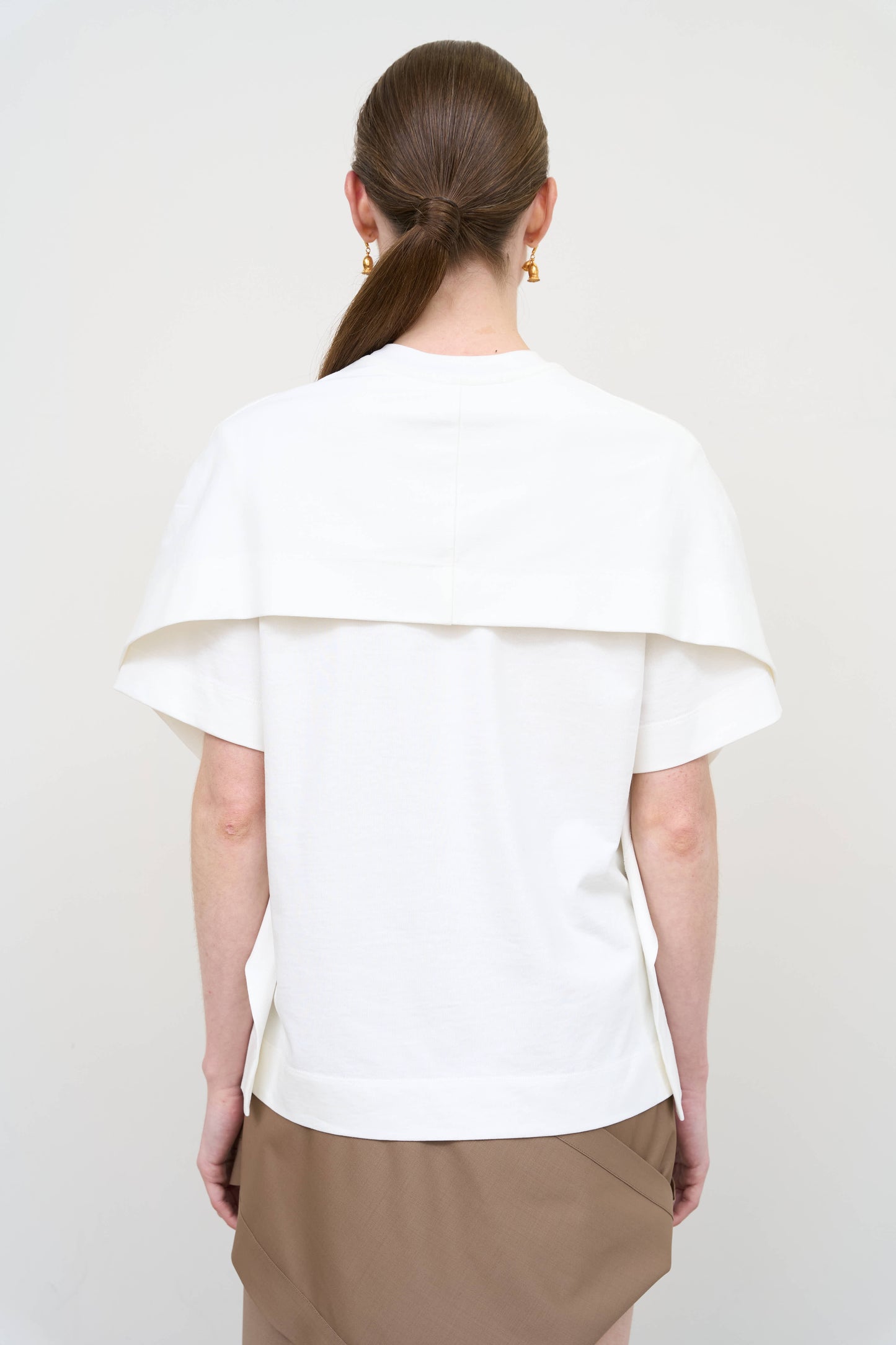 Model is wearing a white overlay cotton T-shirt by Litkovska with relaxed fit and layered architectural design, modern designer women’s T-shirt available at House of Woven Stories