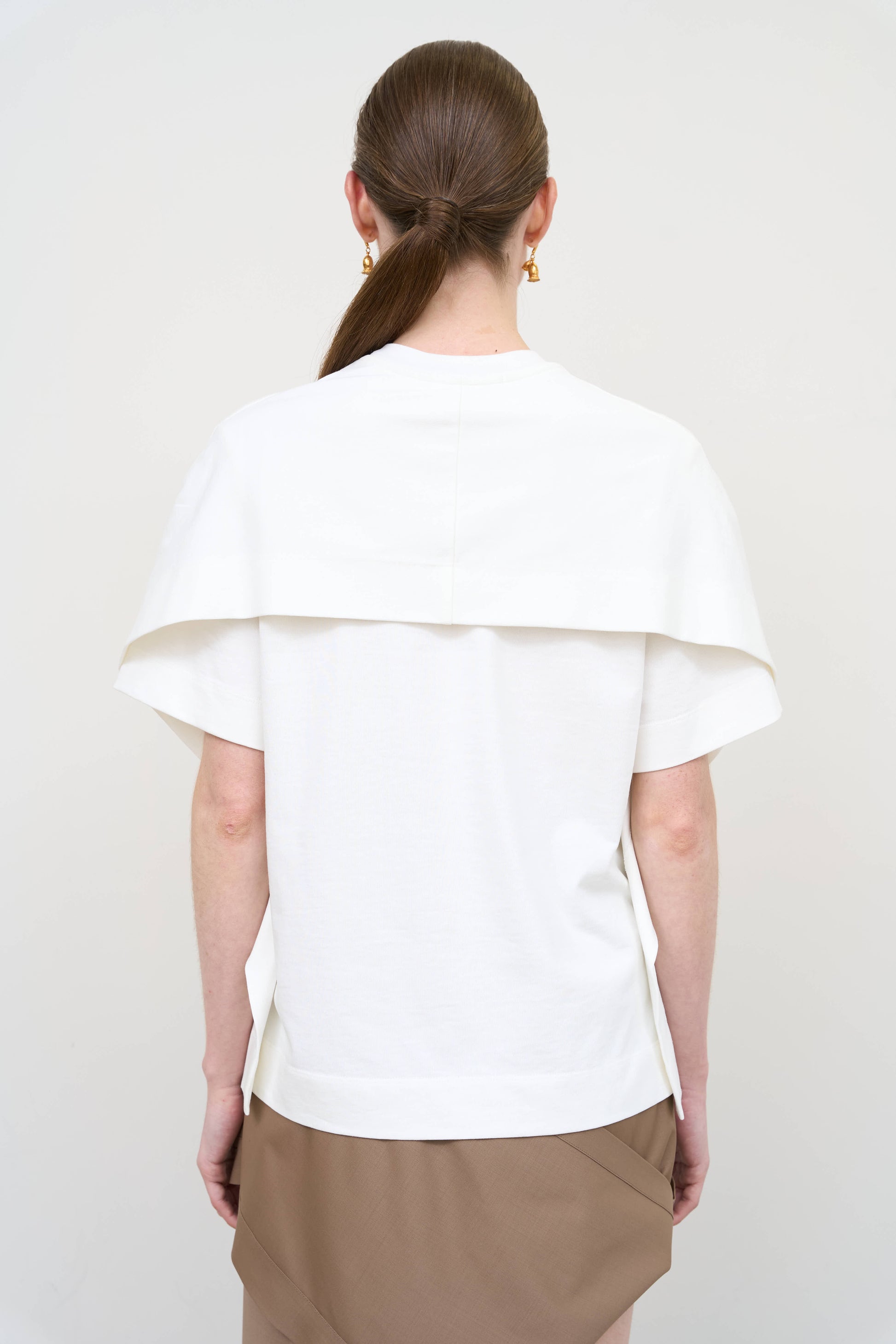 Model is wearing a white overlay cotton T-shirt by Litkovska with relaxed fit and layered architectural design, modern designer women’s T-shirt available at House of Woven Stories