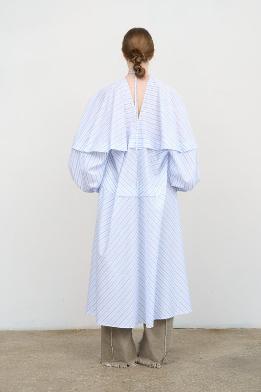 Model is wearing Litkovska blue striped poplin maxi dress with balloon sleeves and sculptural silhouette. A modern, sculptural, and artisanal piece that belongs to the curated selection of House of Nomad Stories.