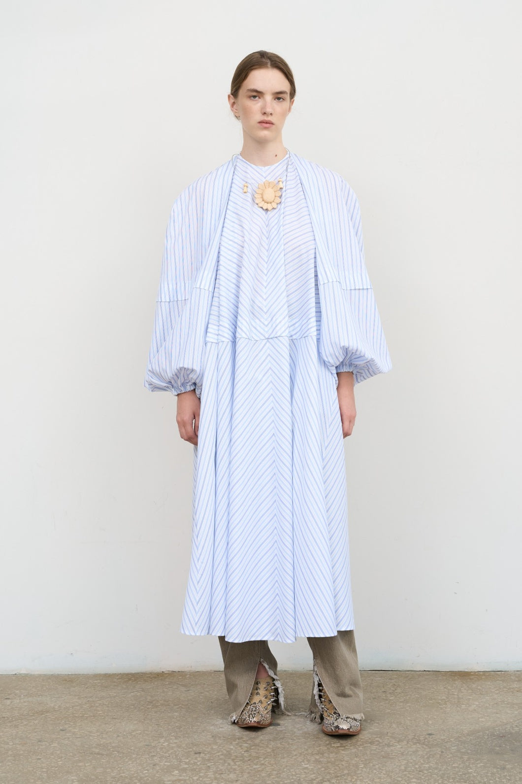 Model is wearing Litkovska blue striped poplin maxi dress with balloon sleeves and sculptural silhouette. A modern, sculptural, and artisanal piece that belongs to the curated selection of House of Nomad Stories.