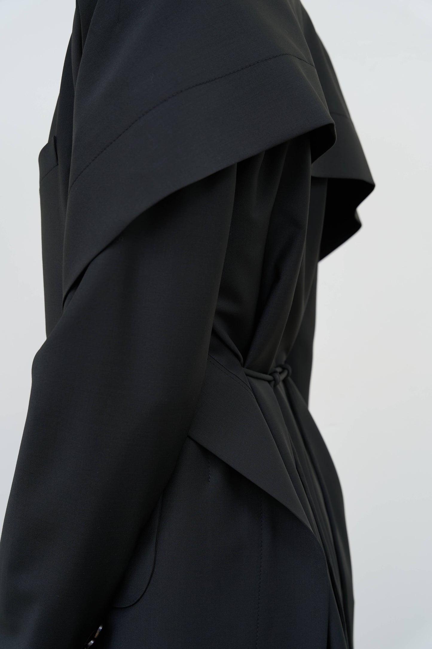 Model is wearing a black tailored wool-blend jacket by Litkovska with capelet overlay and architectural design, designer women’s jacket available at House of Woven Stories